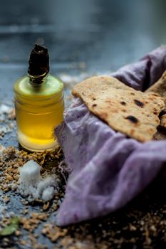 Shot of bhakri in a basket container along with some wheat flour spread on the surface and some cooking oil in a small glass bottle on a black colored surface. close up shot of traditional Gujarati bread Bhakri.