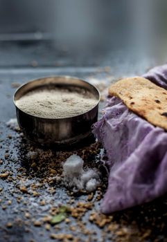 Shot of Gujarati breakfast consisting of round bread bhakri and lasun chutney. Shot of bhakhri, with wheat flour, garlic chutney, salt, and some whole wheat grains on a black glossy surface.