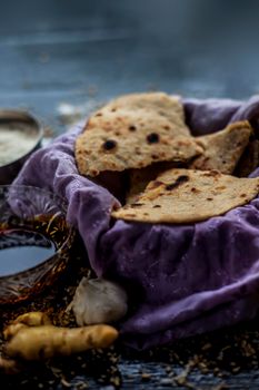 Shot of Gujarati breakfast consisting of round bread bhakri and lasun chutney. Shot of bhakhri, with wheat flour, garlic chutney, salt, ginger, and some whole wheat grains on a black glossy surface.