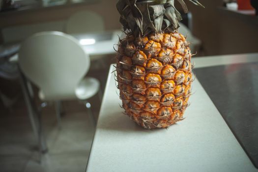 Whole pineapple fruit standing on the kitchen white counter