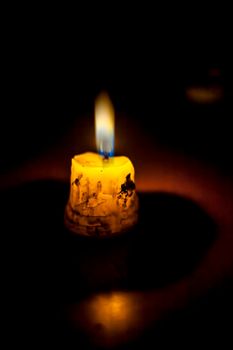 Shot of a single isolated candle burning itself and giving light to its surrounding.