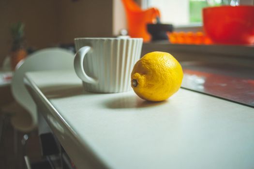 A white cup and lemon on the countertop