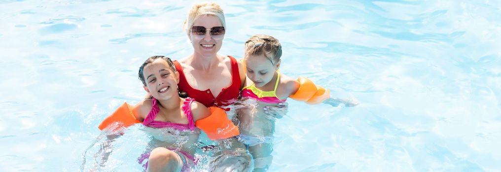 Happy family having fun on summer vacation, playing in swimming pool. Active healthy lifestyle concept.