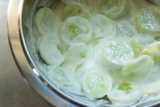 Cucumber salad with cream in a bowl, top view and close up