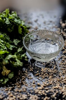 Exfoliating skincare face mask on a black colored surface consisting of some coriander leaves and egg white along with some oats.