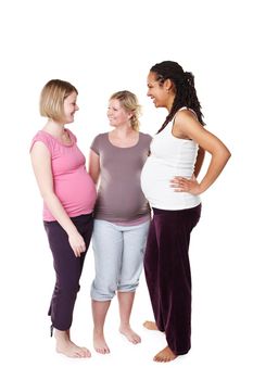 Happy pregnant friends talking in white background studio with pilates, health or yoga clothes. Mother, maternity and communication with women having a pregnancy lifestyle discussion together.