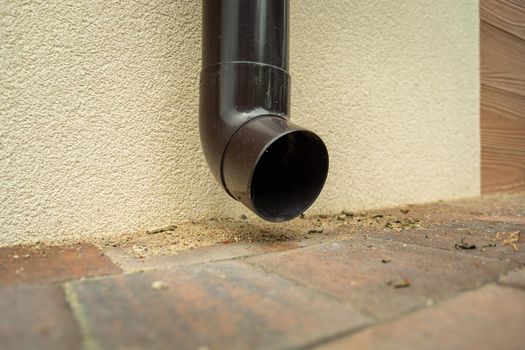 Plastic brown gutter hole near the ground