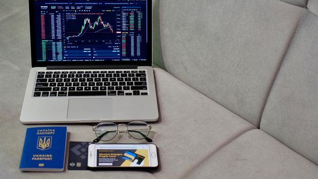 Laptop and phone to buy bitcoin on the Binance crypto exchange for support Ukraine during the market crash. Trading, spot, staking. Workspace freelance flatlay