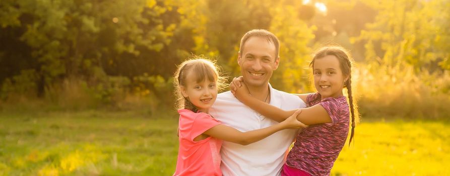 Happy loving family, dad playing with two little cute daughters outdoors at sunset, family relationship and friendship concept