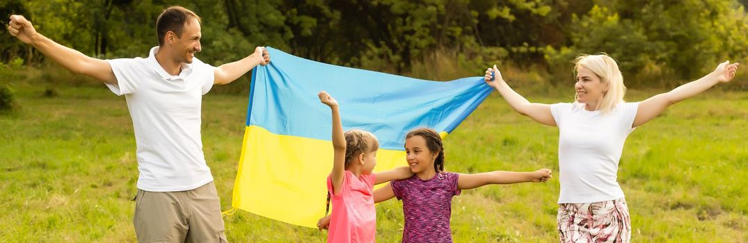 Flag Ukraine in hands of little girl in field. Child carries fluttering blue and yellow flag of Ukraine against background field