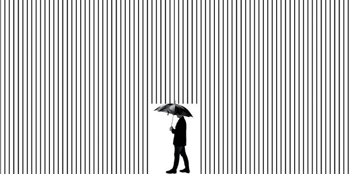 Shot of a man in a suit with an umbrella walking near some illusion like the wall behind him in the background.