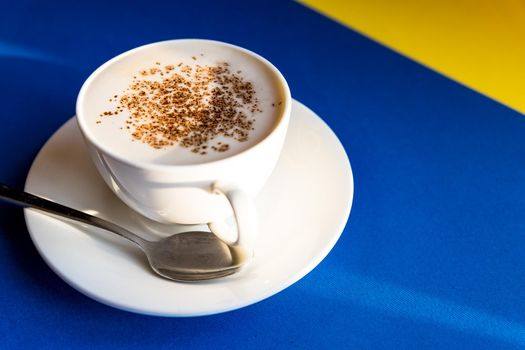 Cappuccino Flat lay, black background, white cup with spoon, coffee beans. Morning coffee in Italy. Close-up on a white cup.