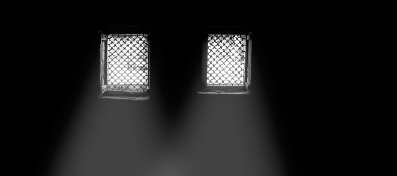 Cinematic dark mood shot of windows with some sunlight coming through in the dark room.