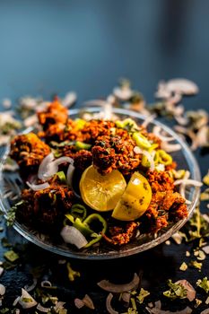 Indian styled meatballs or kabab or kebab on glass plate along with sprinkled cut green chilies and onion rings plus lemon.