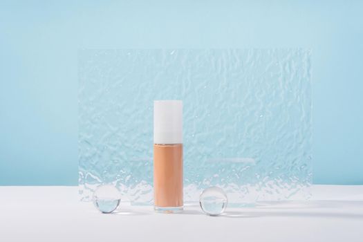 Cosmetic liquid foundation nude cream bottle mockup on blue backdrop. Beige concealer base cosmetics product mock up with stylish props. Skincare beauty primer