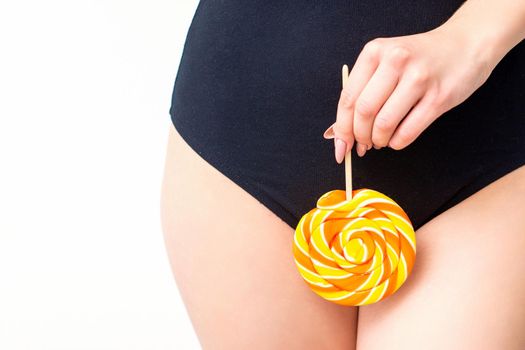Woman holding lollipop candy on bikini zone, the concept of intimate depilation, problems of intimate hygiene