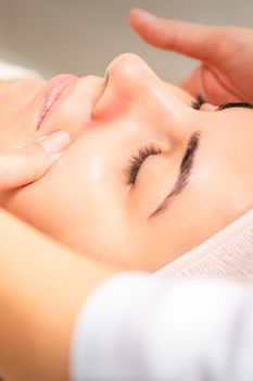 Beautician making lymphatic drainage face massage or facelifting massage at the beauty salon