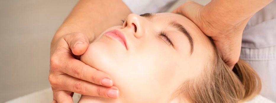 Young caucasian woman receiving a head and chin massage in a spa medical center