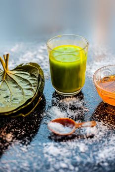 Face mask for controlling oiliness consisting of betel leaves juice, honey, sea-salt on a black wooden surface.