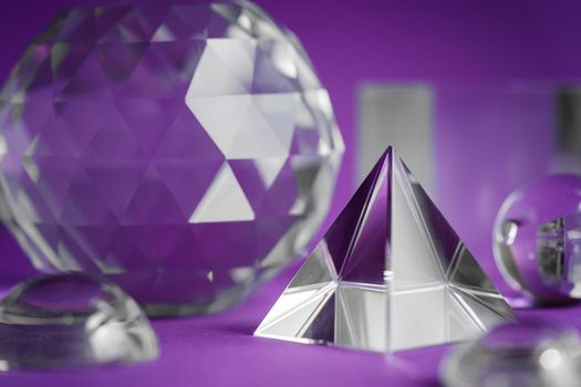 Crystal prism refracting light, magic crystals and pyramid, sphere and cube on purple background. Spiritual healing crystal practice. Feng Shui, good energy flow concept, esoteric background..