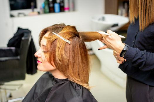 The female client receiving a haircut at the beauty salon, young woman enjoying getting a new hairstyle
