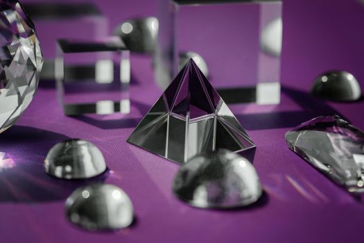 Crystal prism refracting light, magic crystals and pyramid, sphere and cube on purple background. Spiritual healing crystal practice. Feng Shui, good energy flow concept, esoteric background..