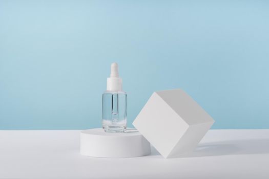 Serum cosmetic bottle with peptides and retinol on platform pedestal on blue background. Oil cosmetics transparent fashion product packaging with stylish props. Serum beauty dropper mock up
