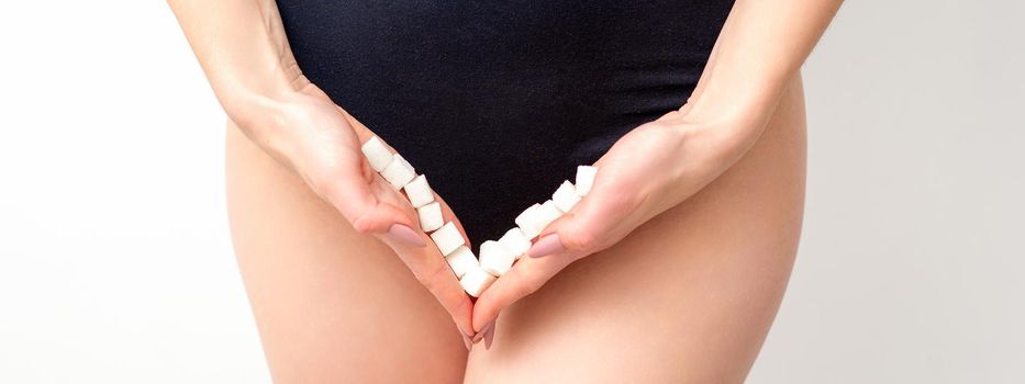 Woman holding sugar cubes on bikini zone, the concept of intimate depilation, problems of intimate hygiene