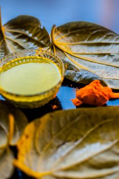 Face mask for preventing acne on a black wooden surface of betel leaves and turmeric powder.