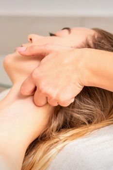 Beautician making lymphatic drainage face massage or facelifting massage at the beauty salon