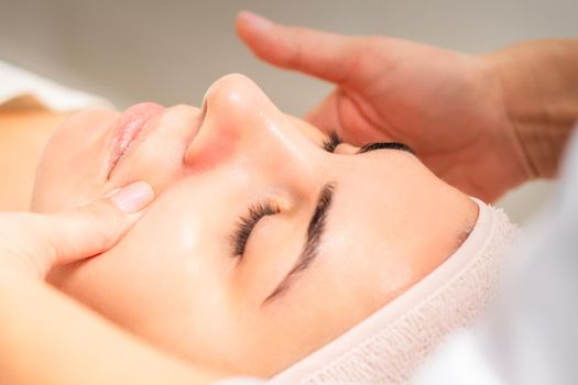 Beautician making lymphatic drainage face massage or facelifting massage at the beauty salon