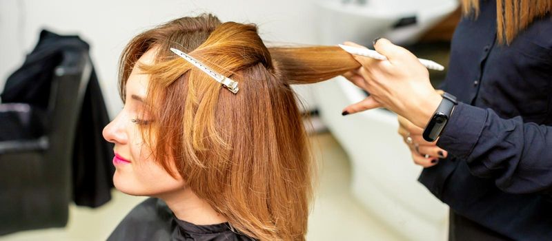 The female client receiving a haircut at the beauty salon, young woman enjoying getting a new hairstyle