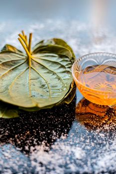 Face mask for controlling oiliness consisting of betel leaves, honey, sea-salt on a black wooden surface.