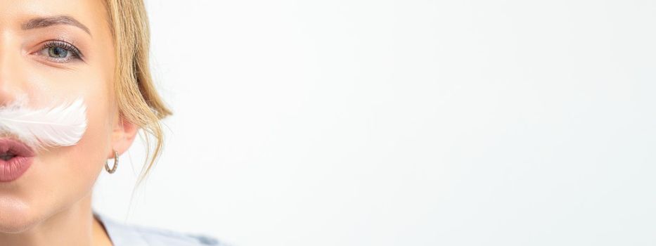 Funny beautician with a white feather-like mustache poses on white background, depilation concept