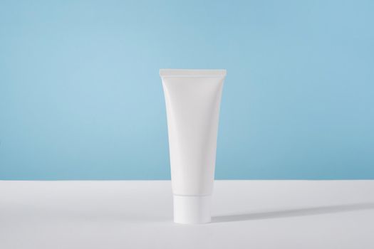 Moisturiser hand cosmetic cream white plastic tube mockup on blue background front view. Blank body and health care beauty product packaging. Hand cream bottle