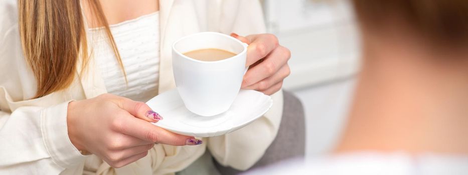 Young caucasian unrecognizable woman holding a cup of hot drink at a doctor's appointment in hospital office