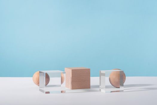 Creative geometric product stage mock up, cosmetic display platform, cosmetics showcase, geometric stand. Wooden and glass cube podium and sphere on blue background for product advertising, front view