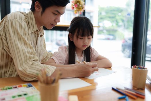 A happy kid and father painting at home. Handmade skills training.