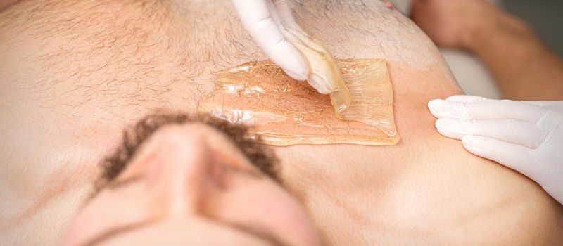 Young caucasian man receiving hair removal from his chest in a beauty salon, depilation men's torso