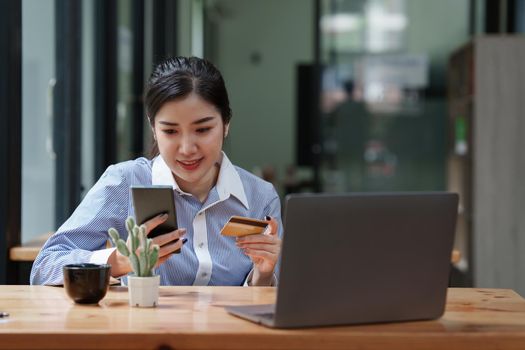 Young person using credit card and laptop computer. Online shopping, e-commerce concept.