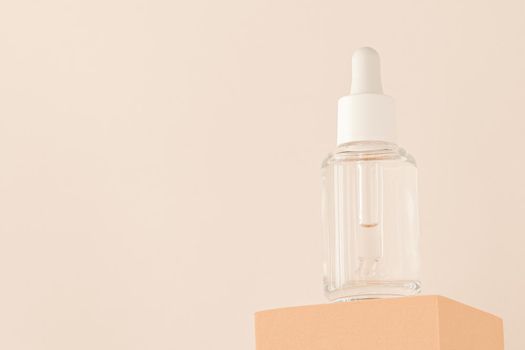 Hyaluronic acid, serum skincare glass bottle on beige podium pedestal, low angle view. Serum product cosmetic with peptide and collagen. Modern brand cosmetics packaging with shadow. Cosmetic showcase