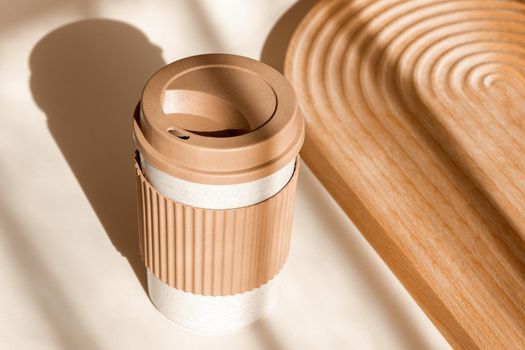 Sustainable bamboo eco friendly cup on natural shadow beige background. Reusable cup, biodegradable travel plastic coffee mug for take away. Zero waste, sustainability concept. Ban single use plastic.