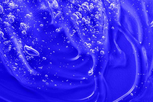 Cosmetic blue gel texture with bubbles. Hyaluronic acid clear serum sample. Liquid antibacterial disinfect smear smudge. Skincare moisturizing product background. Sanitizer swatch. Close-up, macro.