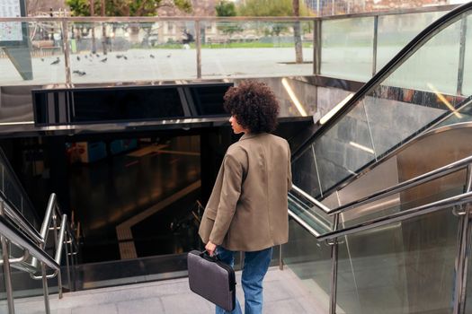 rear view of a successful business woman entering to the subway station with her briefcase, concept of urban lifestyle and public transport, copy space for text