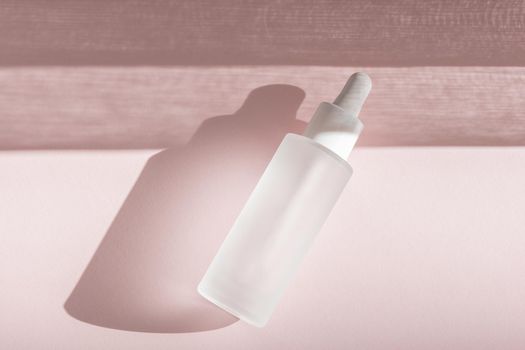 Skin moisturizing serum on pink backdrop with shadow. Beauty skincare essence mockup tincture flat lay, wellness packaging. Hyaluronic acid oil mock up. Lliquid product in glass bottle with dropper