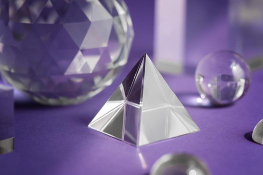 Crystal prism refracting light, magic crystals and pyramid, sphere and cube on purple background. Spiritual healing crystal practice. Feng Shui, good energy flow concept, esoteric background..