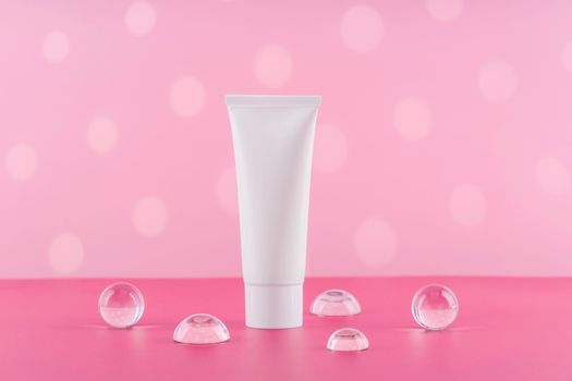 Unbranded cosmetic cream white plastic tube mockup on pink background. Blank body and health care beauty product packaging. Moisturising hand creme bottle with stylish props. Product presentation