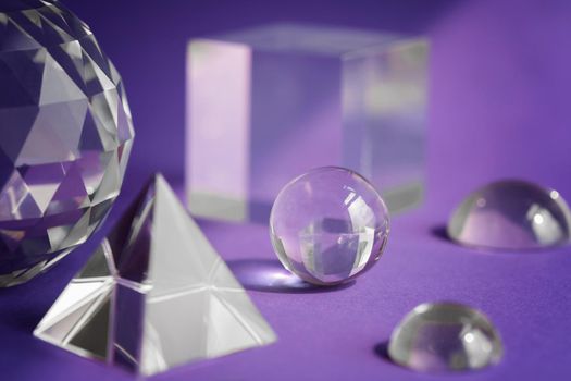 Crystal prism refracting light, magic crystals and pyramid, sphere and cube on purple background. Spiritual healing crystal practice. Feng Shui, good energy flow concept, esoteric background..