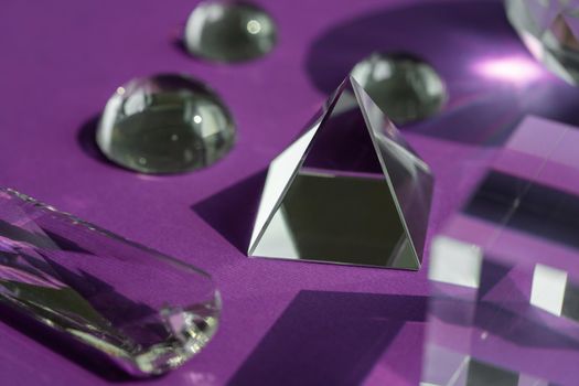 Crystal prism refracting light, magic crystals and pyramid, sphere and cube on purple background. Spiritual healing crystal practice. Feng Shui, good energy flow concept, esoteric background..