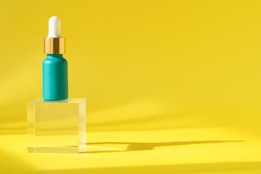 Cosmetics serum product with peptide and collagen, hyaluronic acid skincare bottle on transparent crystall block. Modern packaging with shadows from sun on yellow surface. Cosmetic lotion background